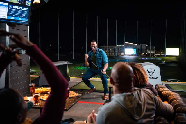 Man pumping fist after golf shot at Topgolf