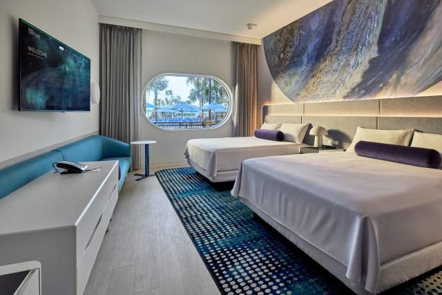 A pool-facing guest room with two queen beds and tranquil planetary elements at Universal Terra Luna Resort