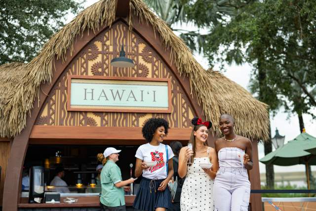 Three friends walk away from the Hawai’i kiosk at the EPCOT International Food & Wine Festival at Walt Disney World Resort.