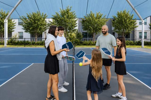 Guests gathering on an outdoor pickleball court at Villatel Resort Orlando, showcasing recreational amenities designed for active vacation experiences and family activities.