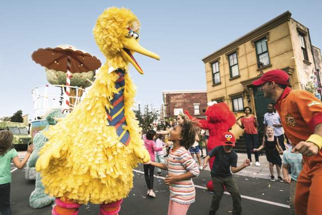 A little girl dancing with Big Bird in the Sesame Street Parade at Seaworld Orlando.