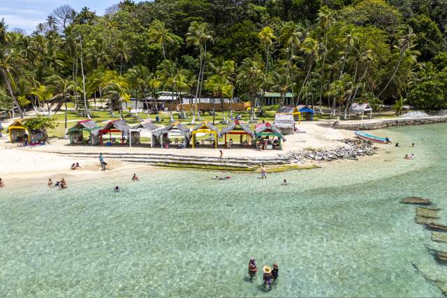 Tourists enjoying a crystal-clear water beach with palm trees in Portobelo, Panama