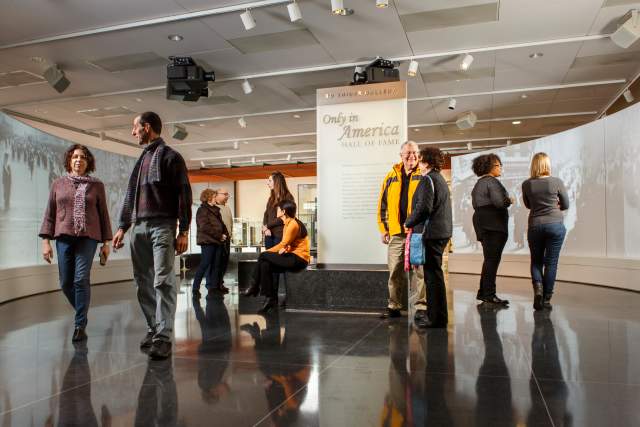 A group of people walking around and reading a display in a museum