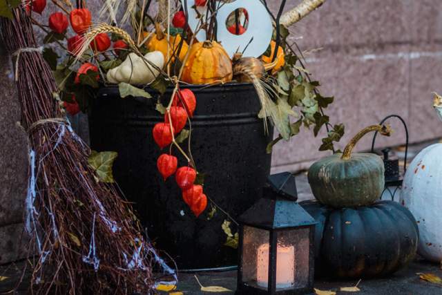 Decorated pumpkins and fall decor leaning up against a brick wall
