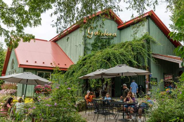 A group of people sitting at tables on a patio outside a winery