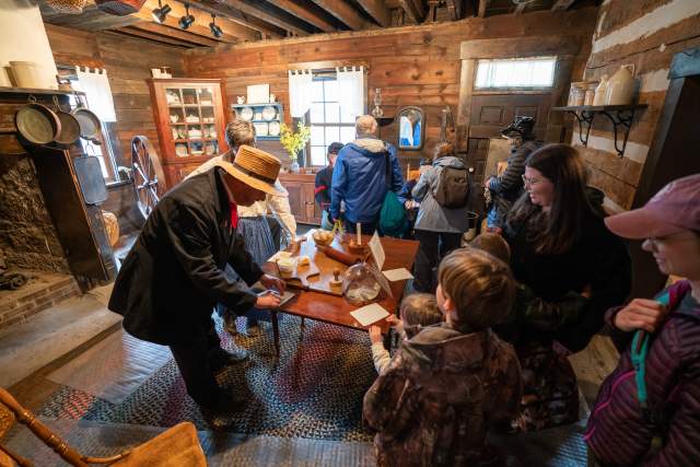 People standing around a table in a rustic cabin looking at maple treats