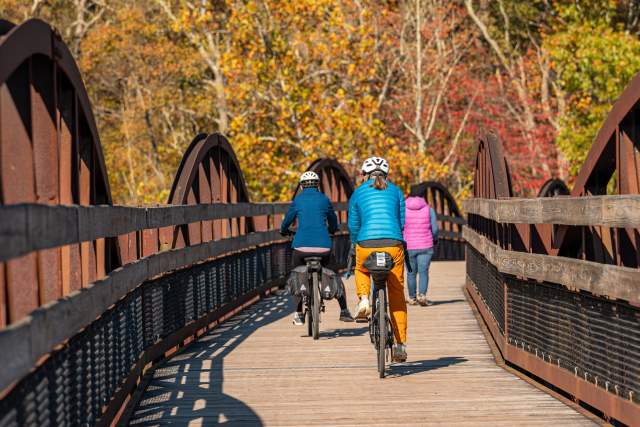 A group of three people riding bikes along and outdoor bridge trail