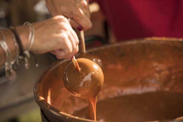 An apple being dipped into a bucket of heated caramel