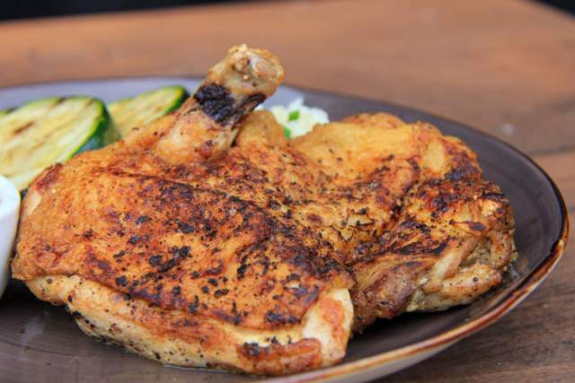 Grilled chicken leg on a plate with grilled veggies