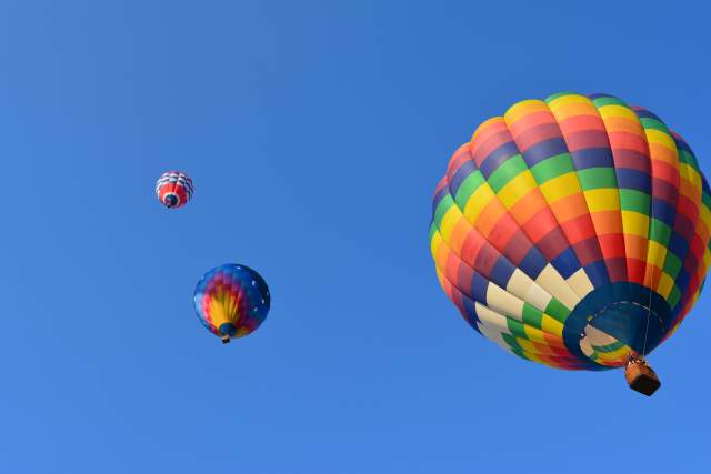 Three hot air balloons floating in a blue sky