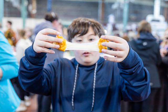Young boy breaking apart a cheese curd