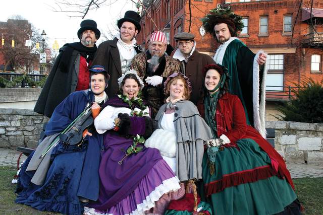 A group of nine people all dressed in old Victorian attire posing for a photo