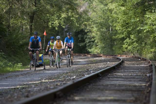 Group of four people biking on a trail next to railroad tracks