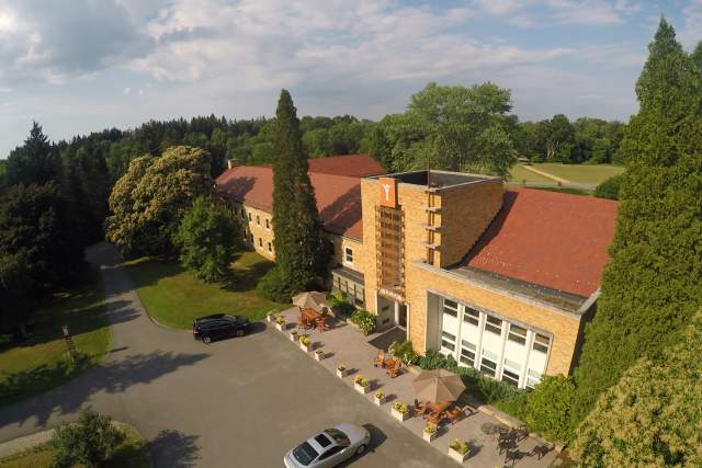 Aerial view of a tan institute on a sunny day with cars parked in front
