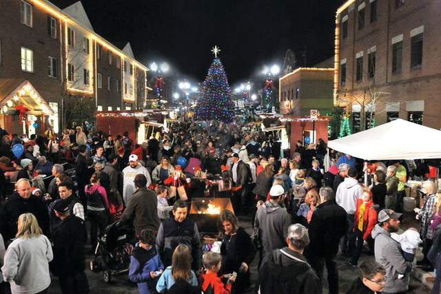 Group of People on main street with holiday lights around Christmas Tree