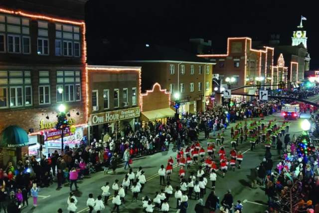 A main street filled with people and holiday lights at night
