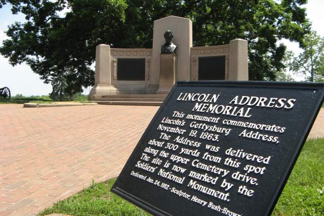 A plaque that reads Lincoln Address Memorial, This monument commemorates Lincolns Gettysburg Address, November 19, 1863. The Address was delivered about 300 yards from this spot along the upper Cemetery drive. The site is now marked by the Soldiers National Monument. Dedicated Jan. 24, 1912 by sculptor Henry Bush-Brown.