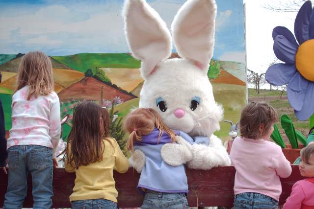 Little kids in a wagon hugging a larger Easter Bunny