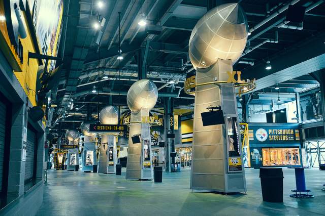 Large steel footballs on stands in Acrisure stadium in Pittsburgh. Signage around the hall reads Pittsburgh Steelers