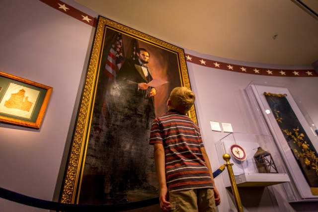 A young boy looking up at a large painting in a museum