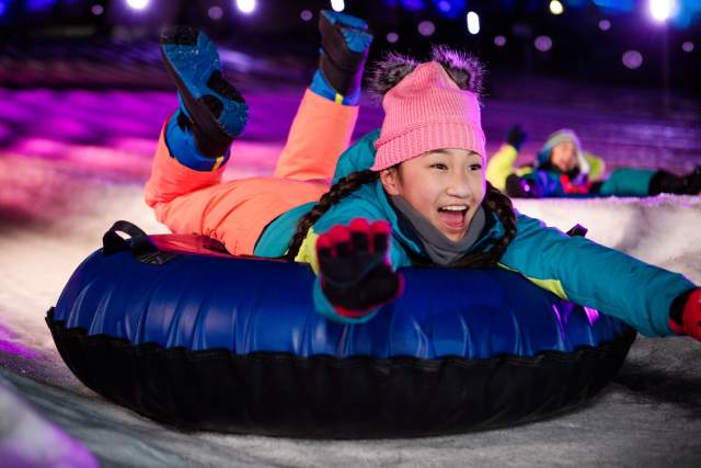 A young girl in snow gear in a snow tube