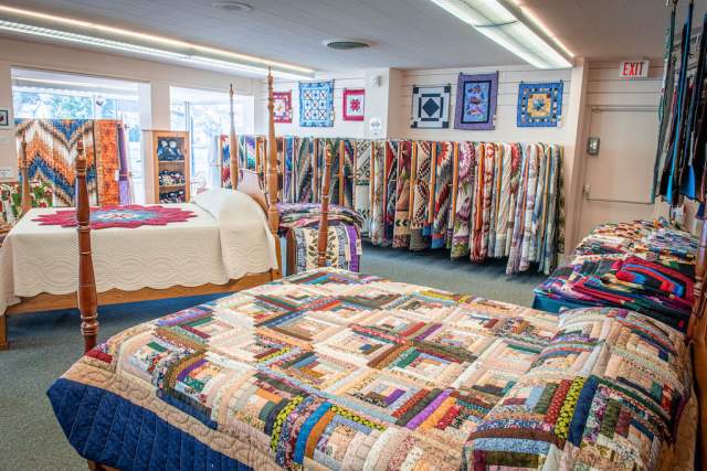 Two full beds with decorative quilts on them in a quilt shop