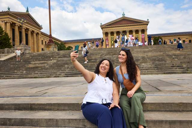Two women sitting on the Rocky Steps in Philadelphia taking a selfie