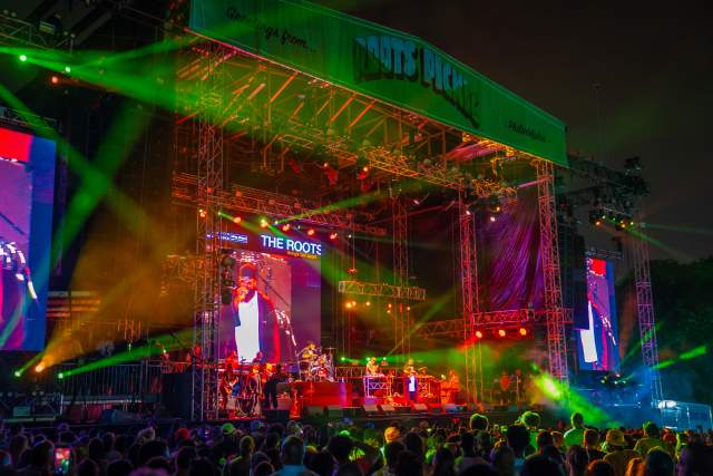 An outdoor concert stage with strobe lights, lit up at night