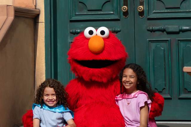A mascot sitting on a stoop with two young girls