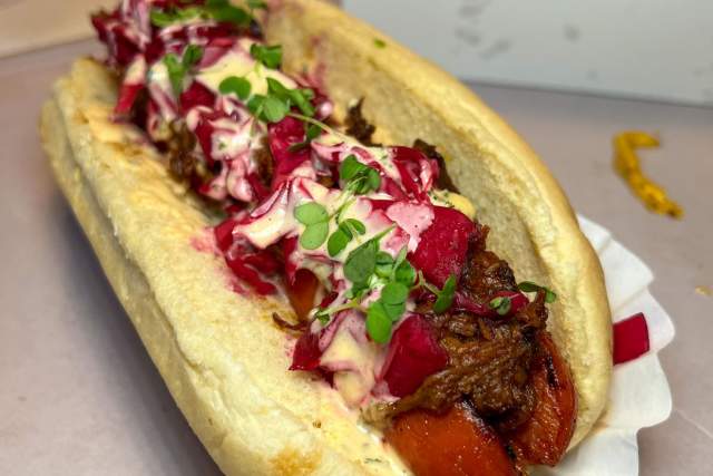 A hot dog in a paper hot dog tray topped with cabbage