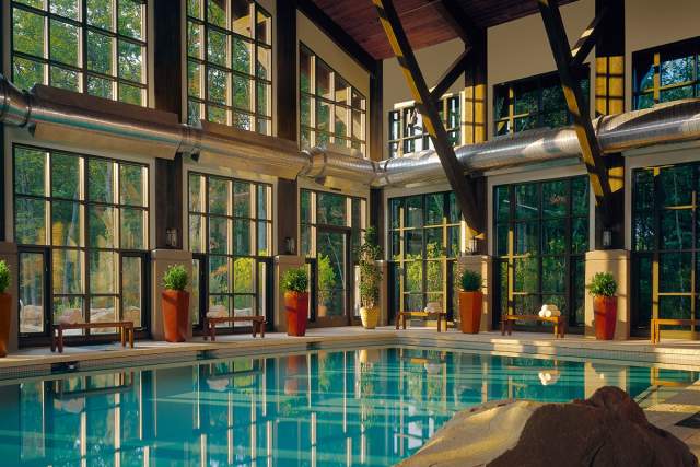 An indoor pool at a spa with a large window wall looking out to a nature scene.