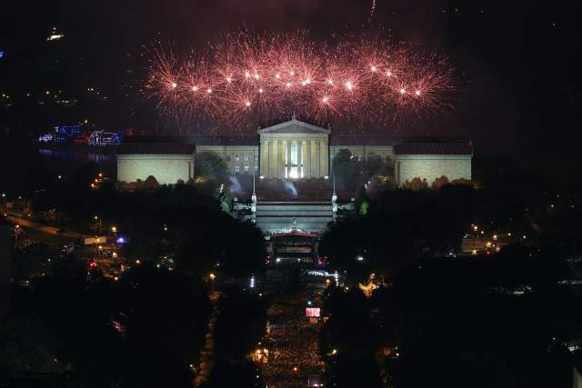 Fireworks going off above the Philadelphia Art Museum at night with a large crowd watching