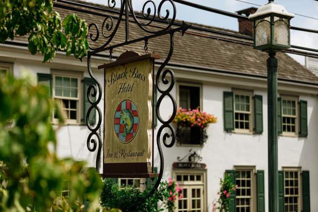 Exterior of an old hotel, with lamp post and a vintage sign out front that reads Black Bass Hotel