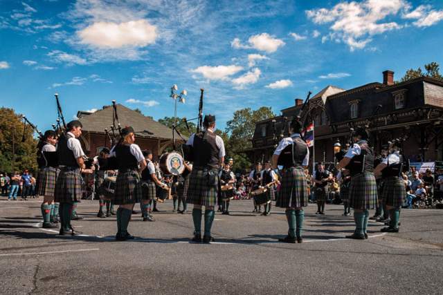 Men and women dressed in traditional Irish kilts standing in a circle playing the bagpipes