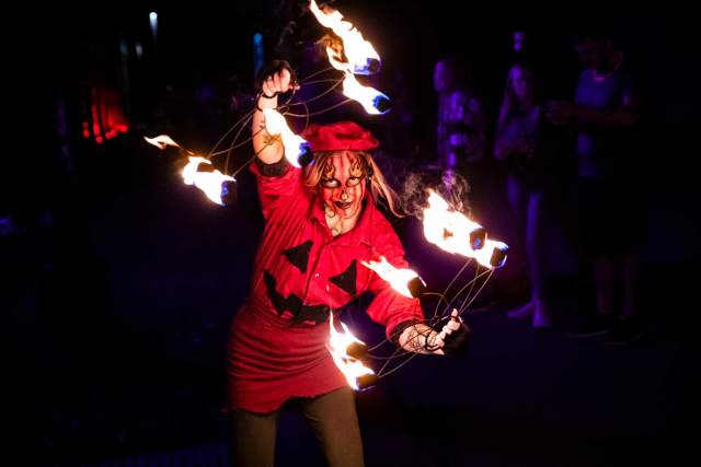 A person in costume juggling torches of fire in the dark at Eastern State Penitentiary.