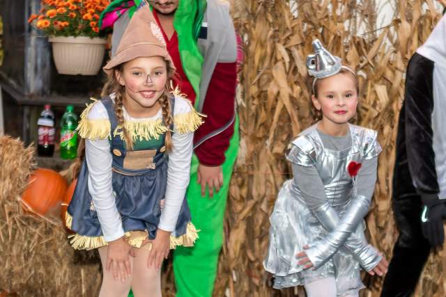 Two girls posing for a photo. One is dressed as a scarecrow and the other is the tin man.