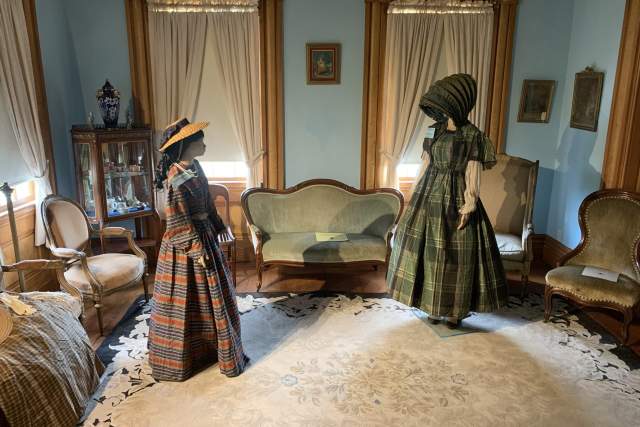 Two statues of women dressed in colonial outfits in a living room