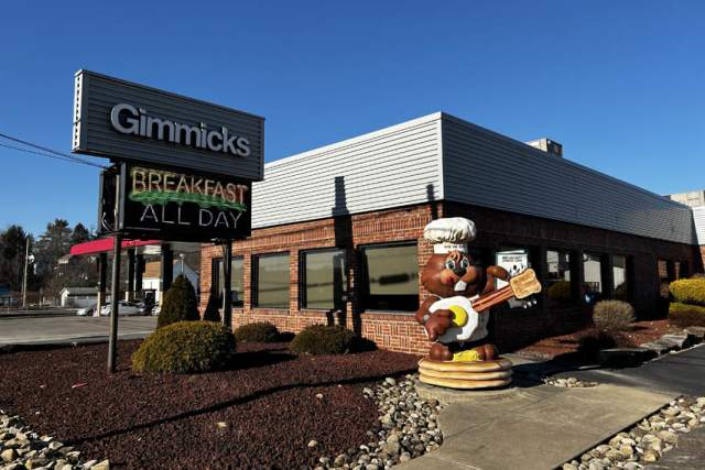 A groundhog statue in front of the entrance of a restaurant with signage that reads Gimmicks Breakfast All Day