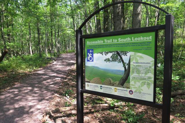 Signage in front of a trail in a wooded forest that reads Accessible Trail to South Lookout