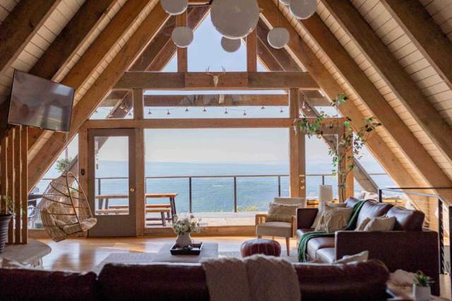 Interior of an A-frame cabin with a balcony looking out to scenery