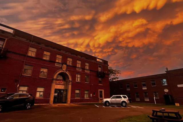 Entrance to a school with cars in the front parking lot and a dark sunset overhead