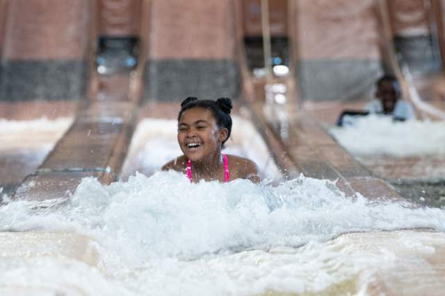 Young girl sliding down a waterslide on her stomach