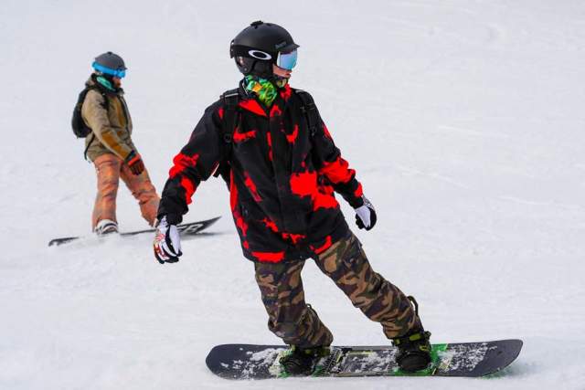 Two persons snowboarding in full winter gear