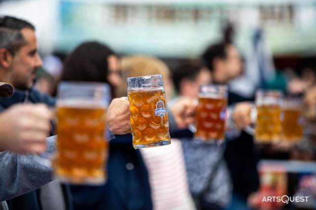 People lined up holding pints of beers up