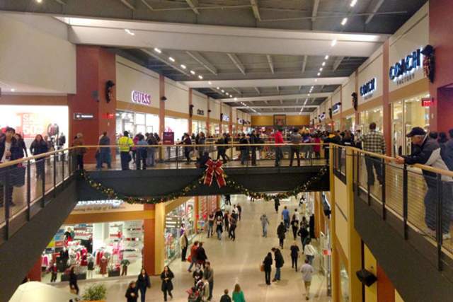 Crowd inside outlet mall with festive garland draped over railings