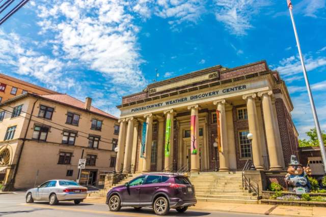 Exterior of the Punxsutawney Weather Discovery Center Building with columns and stairs out front on a sunny day.