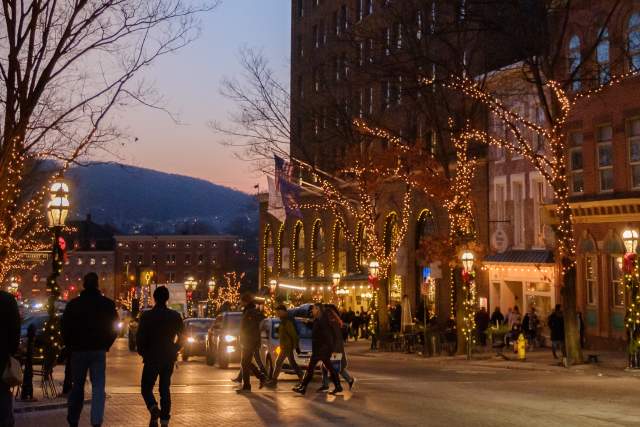 People walking through downtown Bethlehem during the holidays with holidays lights being displayed on buildings.