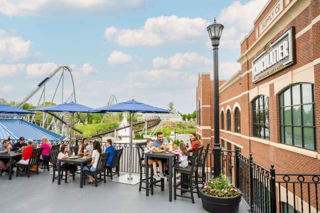 People enjoying food sitting outside on a patio with a view of the amusement park Hersheypark