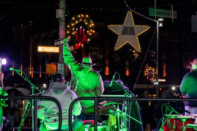 Person on a stage at night with their hand raised in the air with a glowing green light and star hanging overhead