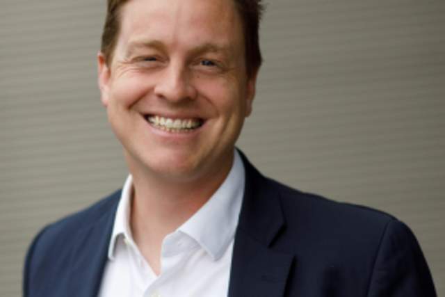 Smiling man in dark blue suit and white button up shirt